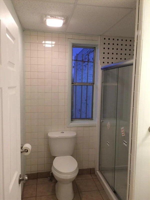 115, 117 N Rollins St, Macon, MO 63552 - bathroom with tile walls, tile patterned flooring, a stall shower, and toilet