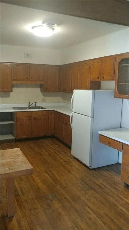 115, 117 N Rollins St, Macon, MO 63552 - kitchen with brown cabinets, freestanding refrigerator, dark wood-type flooring, and a sink
