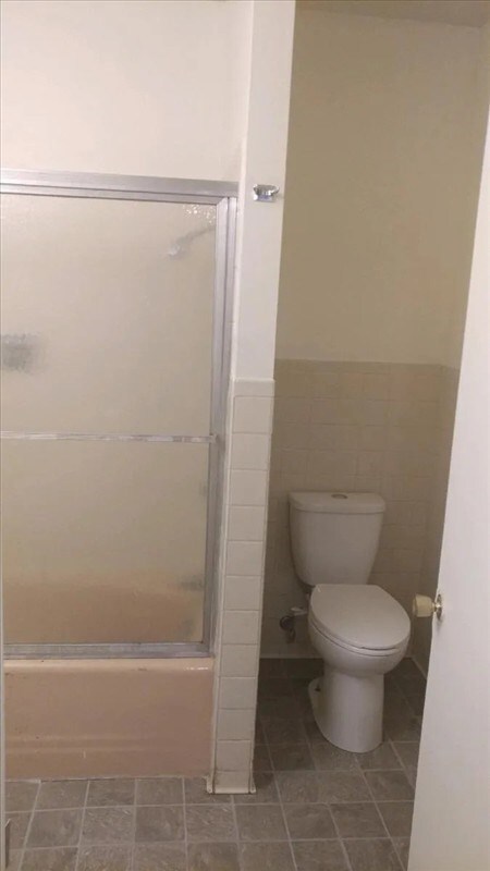 115, 117 N Rollins St, Macon, MO 63552 - bathroom featuring wainscoting, combined bath / shower with glass door, and toilet