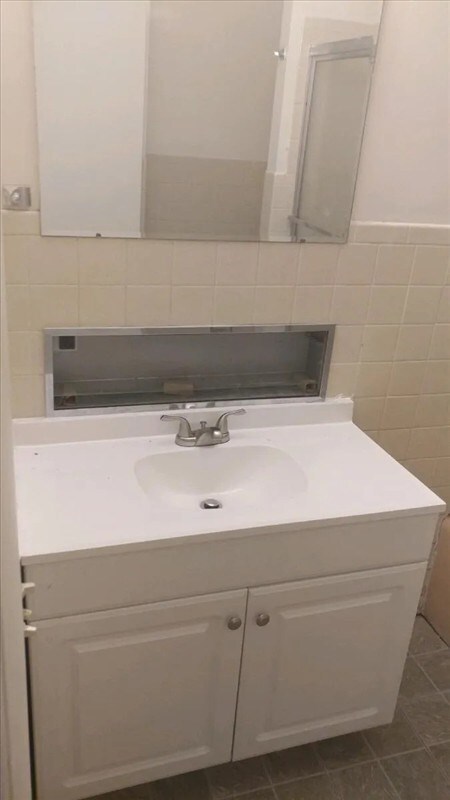 115, 117 N Rollins St, Macon, MO 63552 - bathroom featuring tile walls, vanity, tile patterned flooring, and backsplash