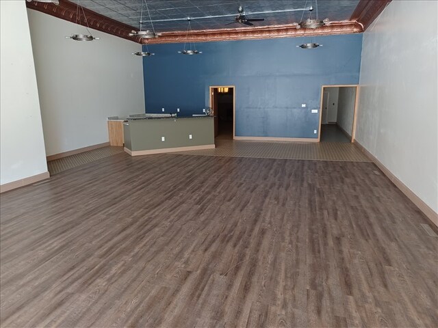 115, 117 N Rollins St, Macon, MO 63552 - unfurnished living room featuring wood finished floors, a high ceiling, and baseboards