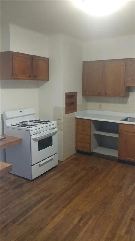 115, 117 N Rollins St, Macon, MO 63552 - kitchen featuring a sink, white range with gas cooktop, dark wood-style floors, and light countertops