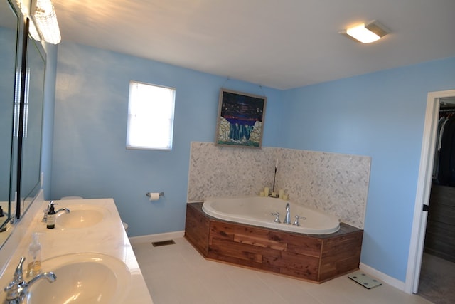 bathroom featuring baseboards, visible vents, a sink, and a garden tub