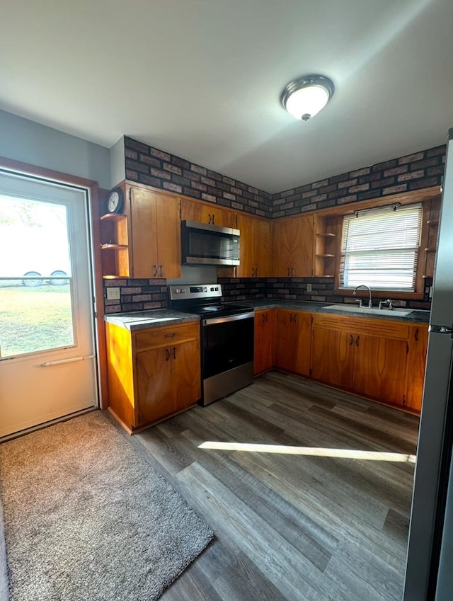 kitchen with stainless steel appliances, brown cabinetry, a sink, and open shelves