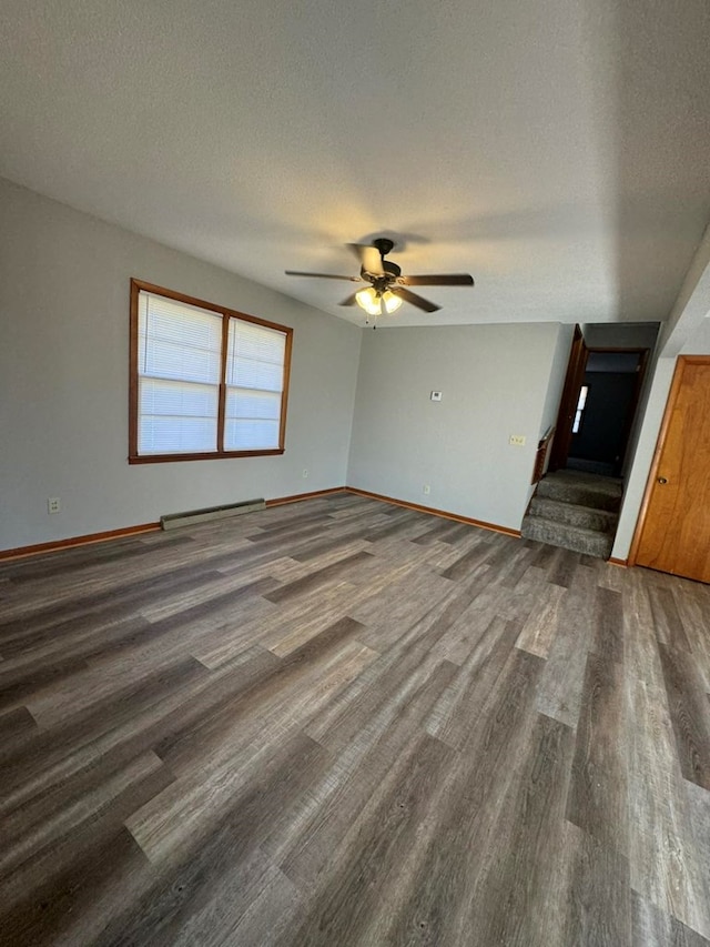 interior space featuring a textured ceiling, wood finished floors, and baseboards