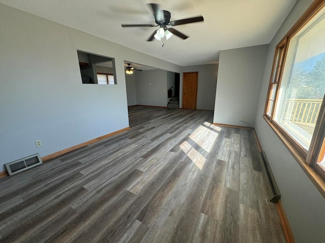 spare room featuring baseboards, visible vents, wood finished floors, baseboard heating, and a textured ceiling