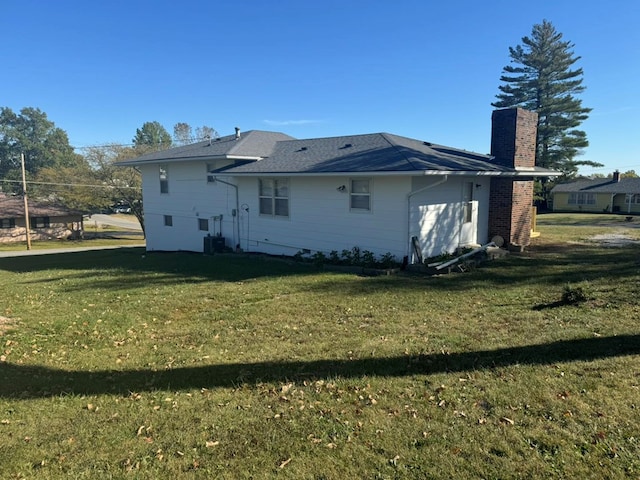 back of house with central AC, a lawn, and a chimney