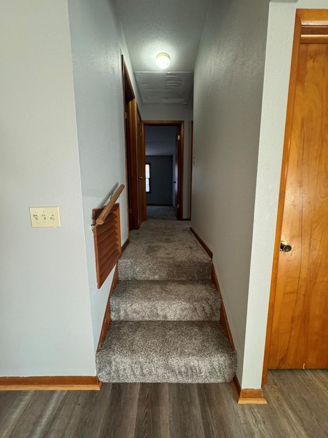 staircase featuring wood finished floors and baseboards