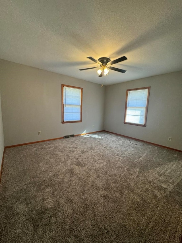 carpeted spare room with visible vents, ceiling fan, a textured ceiling, and baseboards