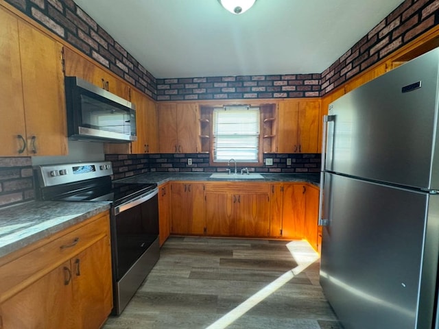 kitchen with wood finished floors, stainless steel appliances, open shelves, and a sink