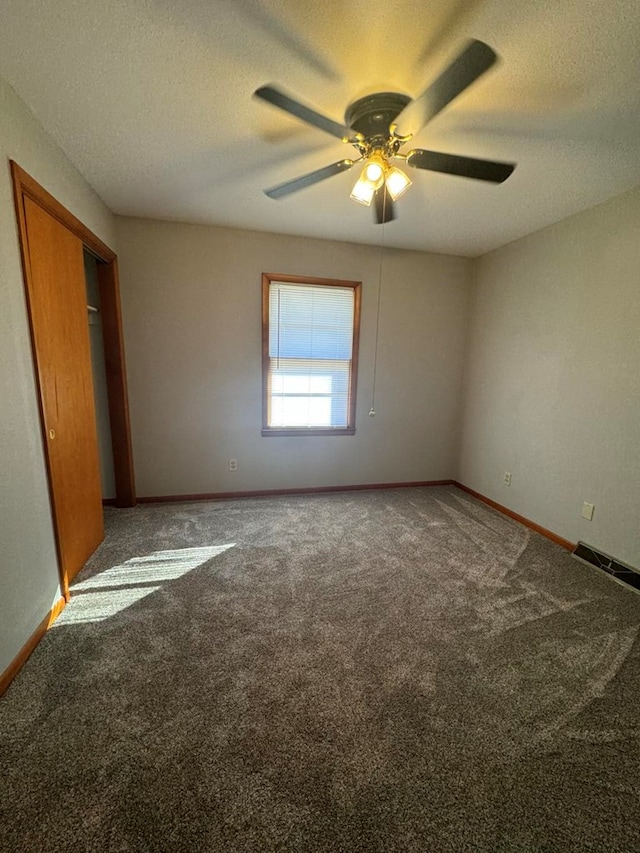 carpeted empty room featuring a ceiling fan, visible vents, a textured ceiling, and baseboards