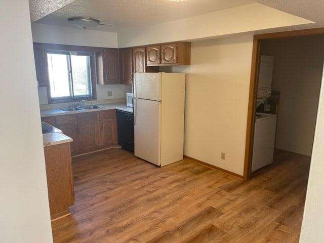 1302 Queens Ct, Kirksville, MO 63501 - kitchen with freestanding refrigerator, a sink, stacked washer / drying machine, dishwasher, and light wood finished floors