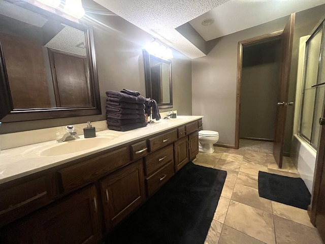 full bathroom with a sink, double vanity, toilet, and a textured ceiling