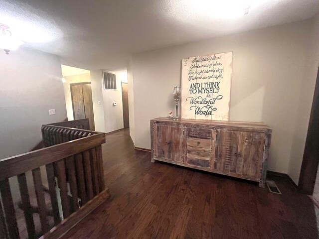 hallway featuring wood finished floors, an upstairs landing, and visible vents