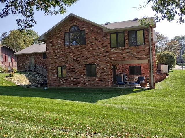 back of property with brick siding, a yard, and a patio