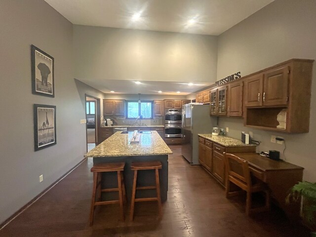 kitchen with a breakfast bar area, a center island, a sink, freestanding refrigerator, and light stone counters