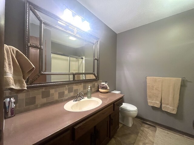 full bathroom featuring toilet, a shower with shower door, a textured ceiling, backsplash, and vanity