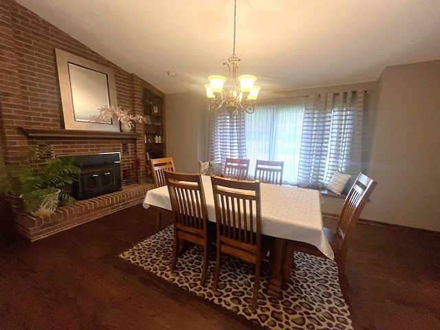 dining area with a brick fireplace, a notable chandelier, wood finished floors, and vaulted ceiling