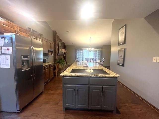 kitchen featuring pendant lighting, a kitchen island, black electric stovetop, stainless steel fridge with ice dispenser, and a notable chandelier