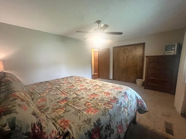 bedroom featuring ceiling fan, light carpet, and a closet