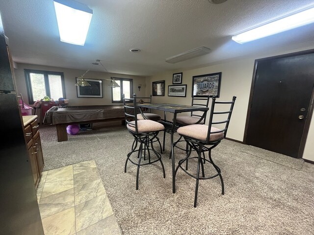 dining room with light carpet, pool table, and a textured ceiling