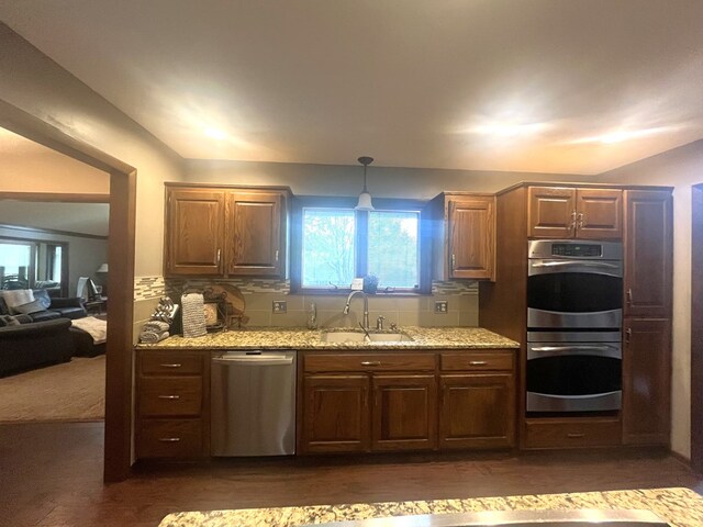 kitchen with light stone counters, dark wood finished floors, appliances with stainless steel finishes, and a sink