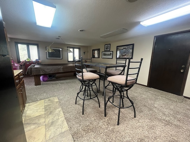 dining room with pool table, a textured ceiling, and light carpet