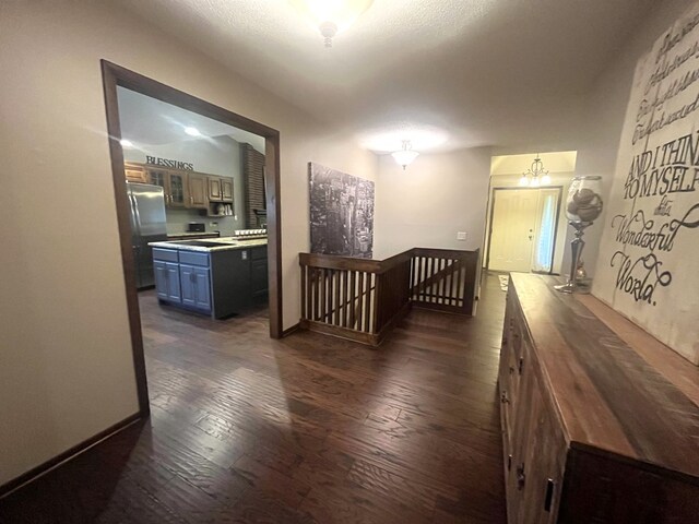 hall featuring dark wood finished floors, an upstairs landing, and baseboards