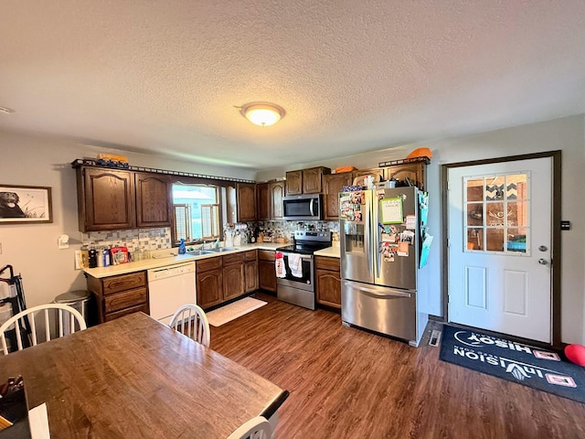 408 Clay St, Edina, MO 63537 - kitchen with stainless steel appliances, light countertops, dark wood-type flooring, a sink, and tasteful backsplash