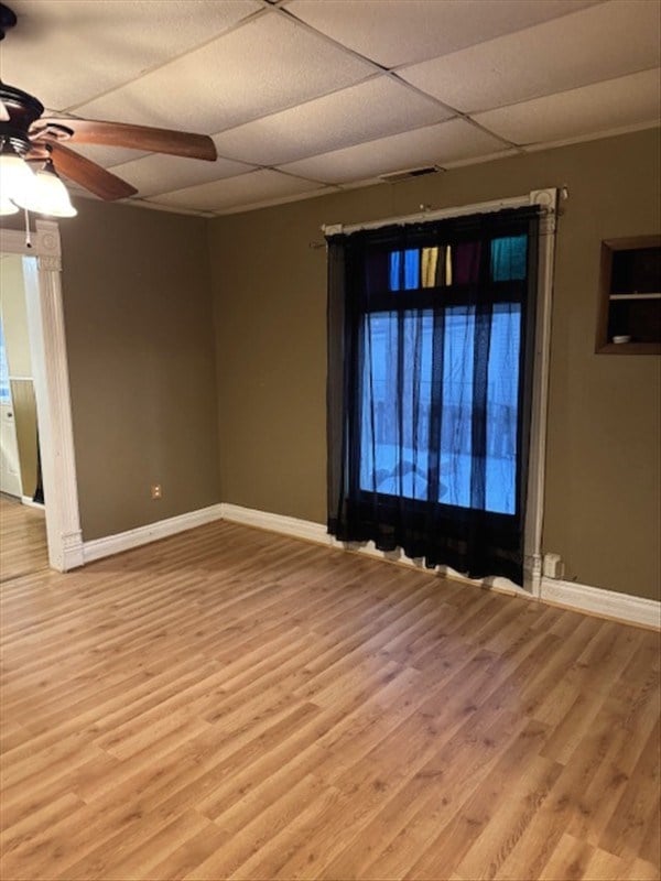 empty room featuring a paneled ceiling, light hardwood / wood-style floors, and ceiling fan