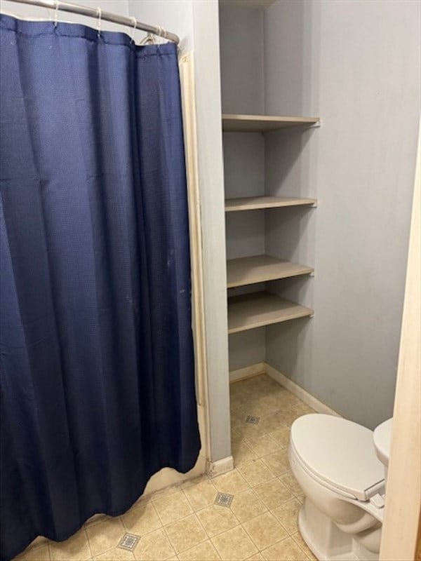 bathroom featuring walk in shower, tile patterned flooring, and toilet