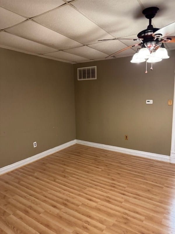 unfurnished room featuring a paneled ceiling, ceiling fan, and light hardwood / wood-style floors