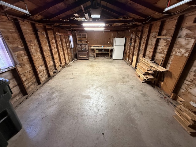 basement with freestanding refrigerator and a garage