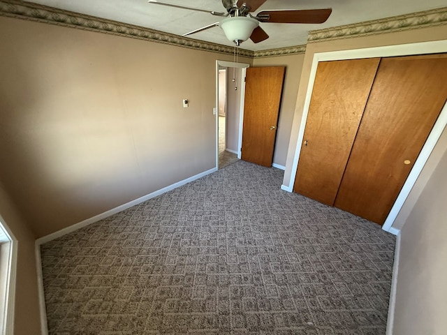 unfurnished bedroom with baseboards, carpet floors, ceiling fan, a closet, and crown molding