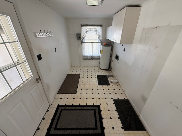 laundry room featuring baseboards, cabinet space, light floors, and water heater