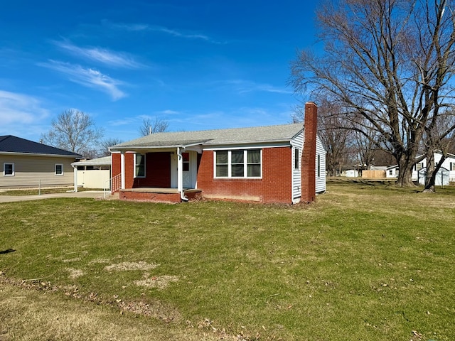 view of front of property with driveway, a front yard, brick siding, and a chimney