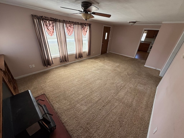 unfurnished living room with a wealth of natural light, a ceiling fan, baseboards, and carpet floors