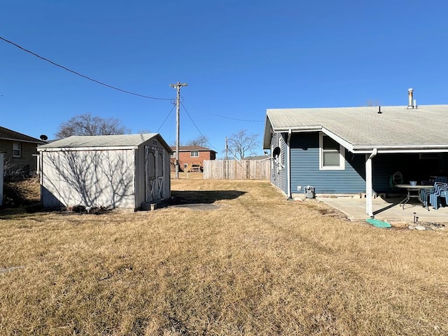 view of yard featuring an outbuilding, a patio, a shed, and fence