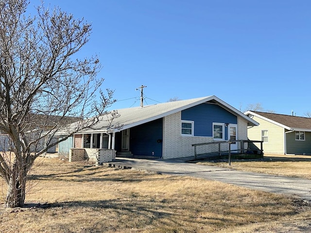 back of property featuring a carport, brick siding, and driveway