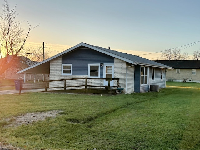 back house at dusk featuring a yard and cooling unit