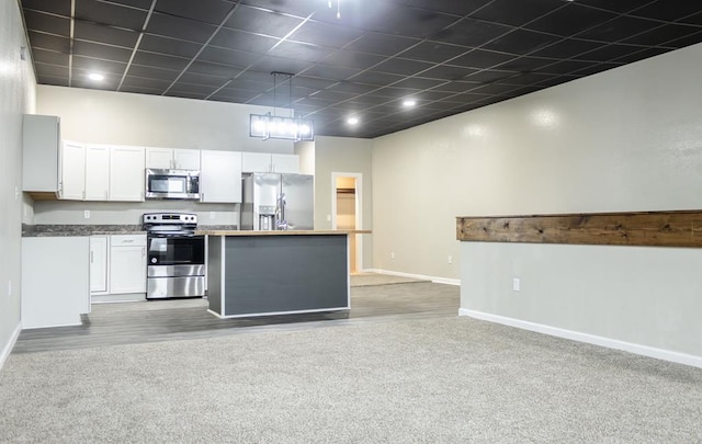 kitchen with white cabinets, a center island, light carpet, and appliances with stainless steel finishes