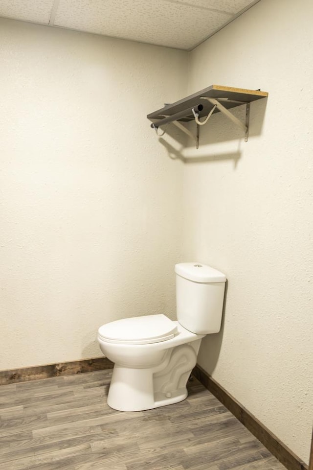 bathroom with toilet, a drop ceiling, and hardwood / wood-style flooring