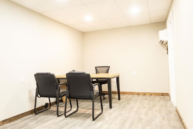 dining room with a paneled ceiling, light hardwood / wood-style floors, and a wall unit AC