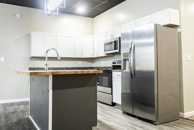 kitchen with light hardwood / wood-style floors, white cabinetry, and stainless steel appliances