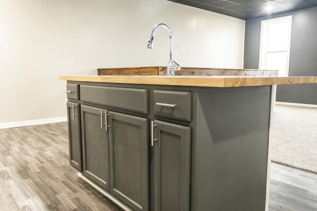 kitchen with a center island with sink, light hardwood / wood-style floors, and wood counters