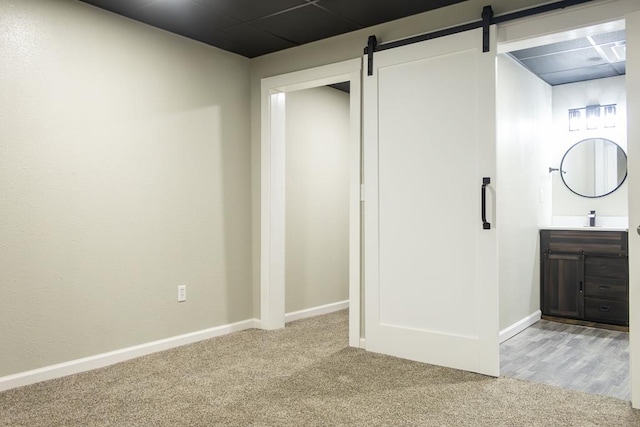 unfurnished bedroom with a barn door, light colored carpet, and sink