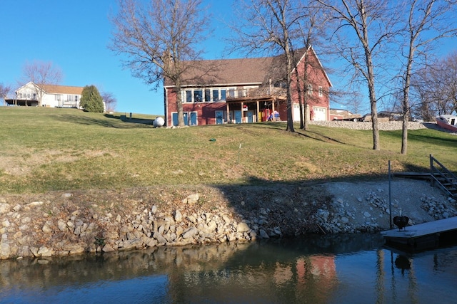 rear view of house with a yard and a deck with water view