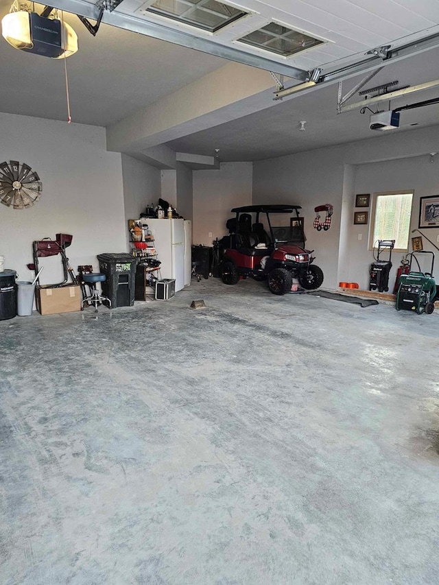 garage featuring white refrigerator and a garage door opener