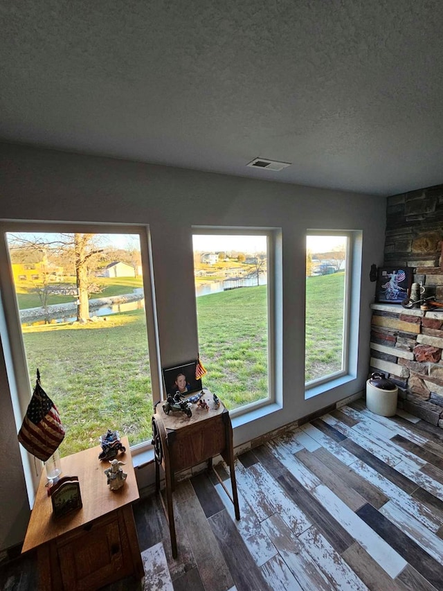 interior space with a water view, wood-type flooring, and a textured ceiling