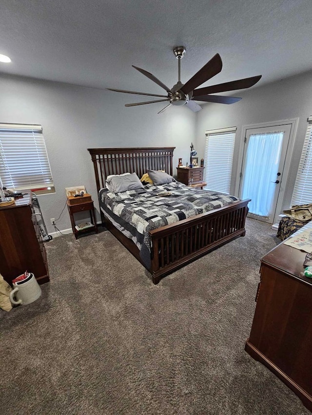 bedroom featuring ceiling fan, dark carpet, and a textured ceiling